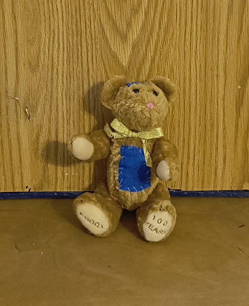 Patches Teddy Bear with a blue belly patch and gold ribbon